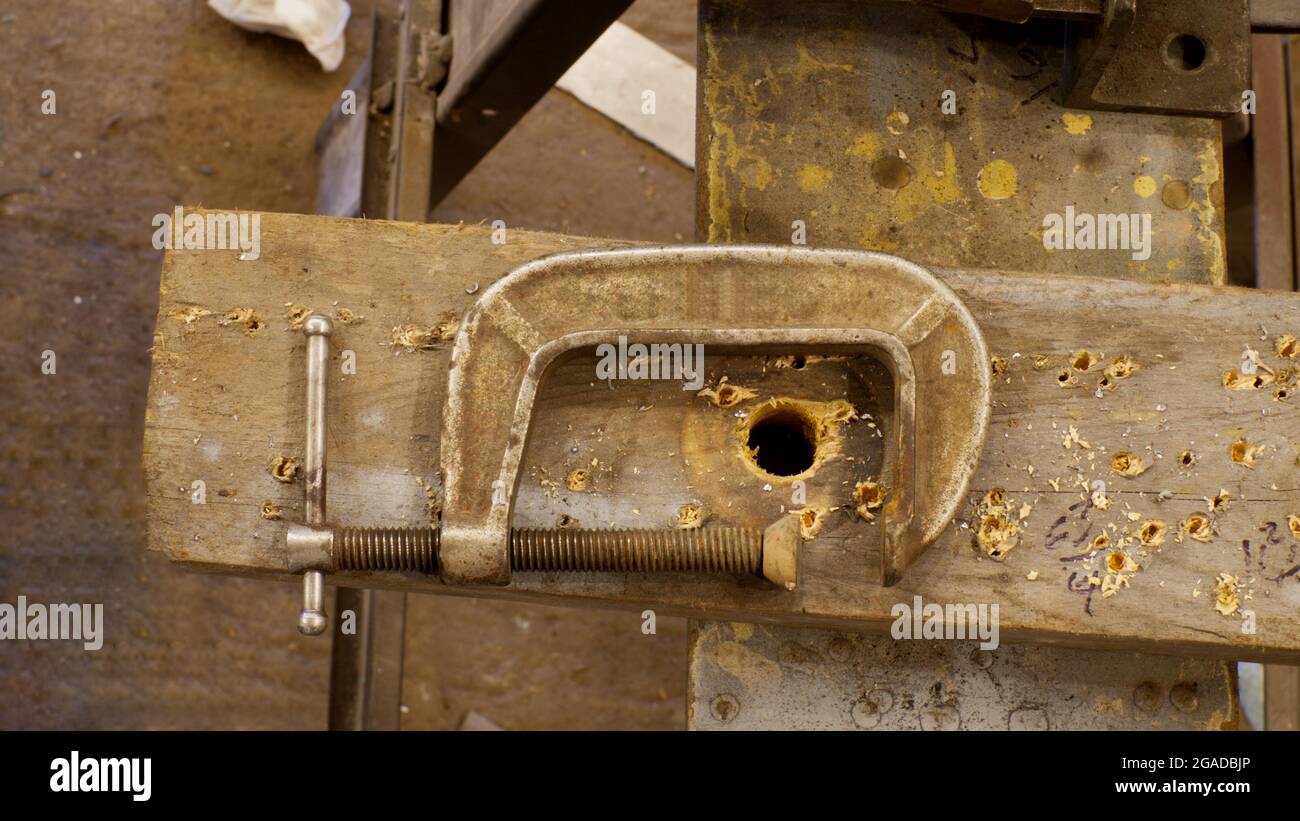 Eine C-Klemme auf einem Holzstück in einer Werkstatt Stockfoto