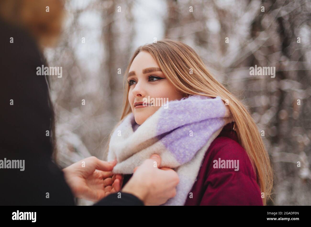 Beschnittenes Foto von schönen jungen Teenager-Paar verbringen Zeit zusammen draußen im kalten Winter, Kerl Richten gestrickten Mädchen Schal, um sie warm zu halten Stockfoto