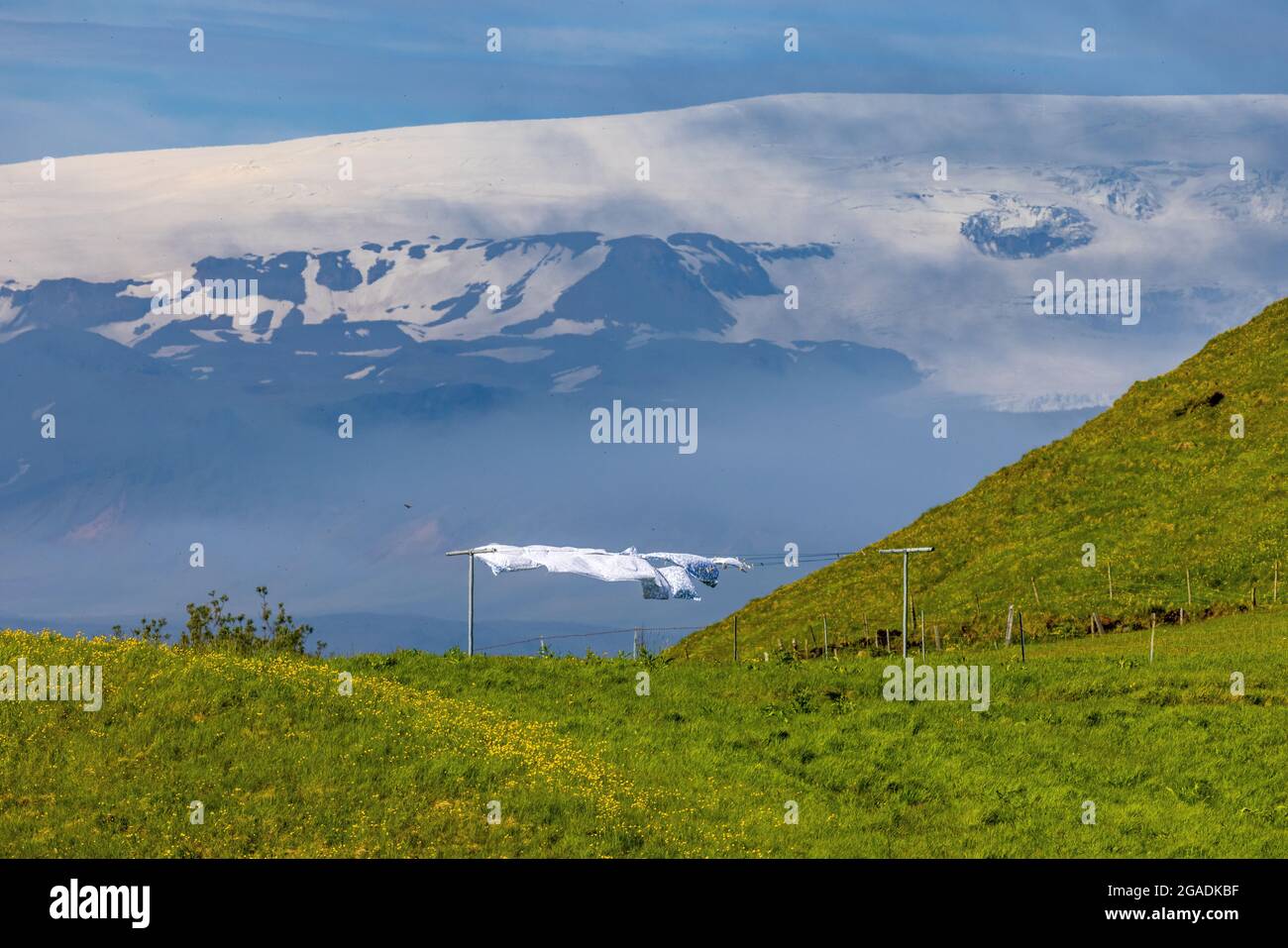 Starke isländische Winde wehen die Wäsche trocken auf der Linie am Hang über dem Strand von Reynisfjoru mit dem Myrdalsjokull-Gletscher dahinter Stockfoto