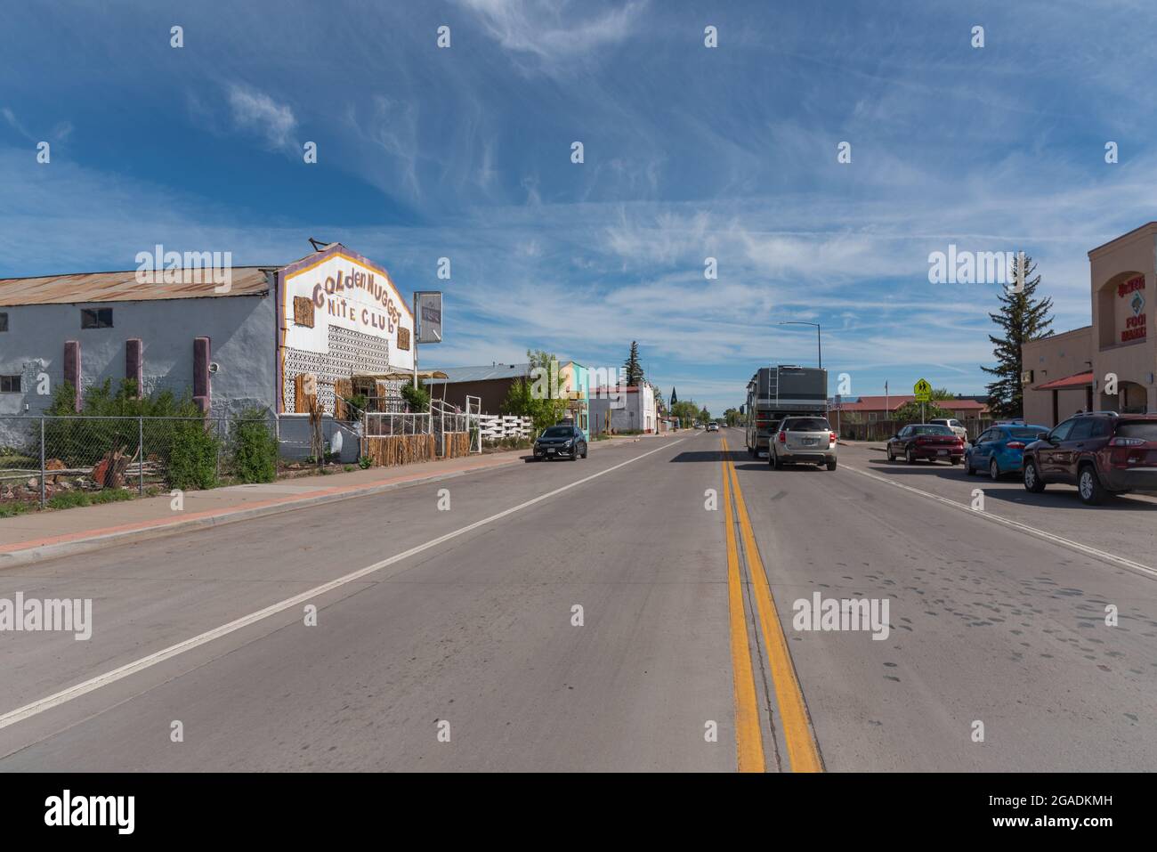 Blick auf den U.S. Highway 285, eine zweispurige Autobahn, die durch das historische Viertel der Kleinstadt in Antonito, Colorado, führt, wobei ein Wohnmobil ein Auto schleppt. Stockfoto