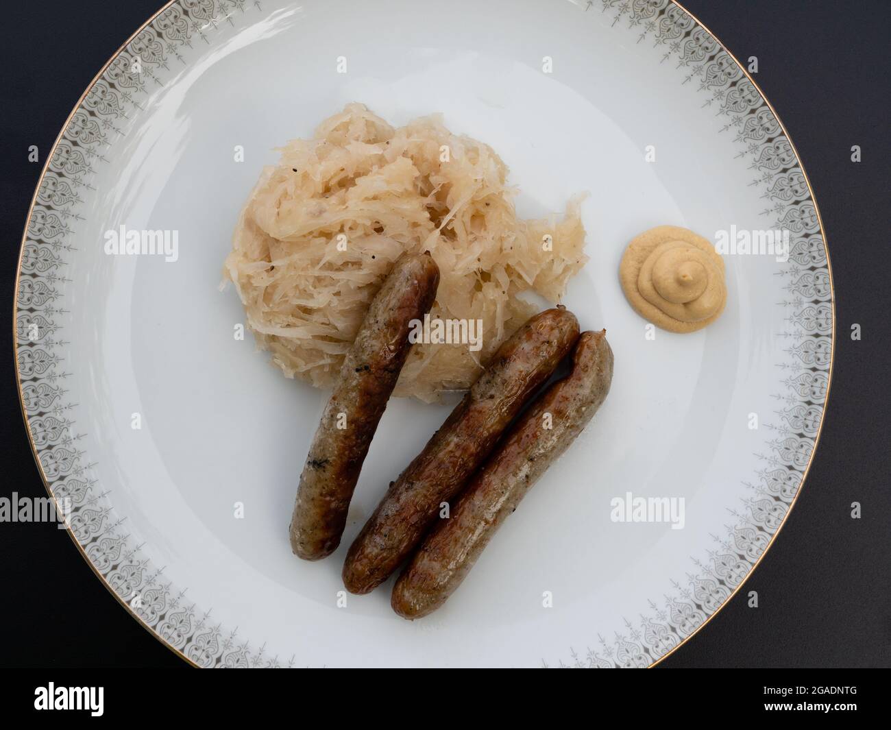 Nürnberger Grillwurst oder Nürnberger Rostbratwurst mit Sauerkraut oder saurem Kohl und Senf auf weißem Teller Draufsicht Stockfoto