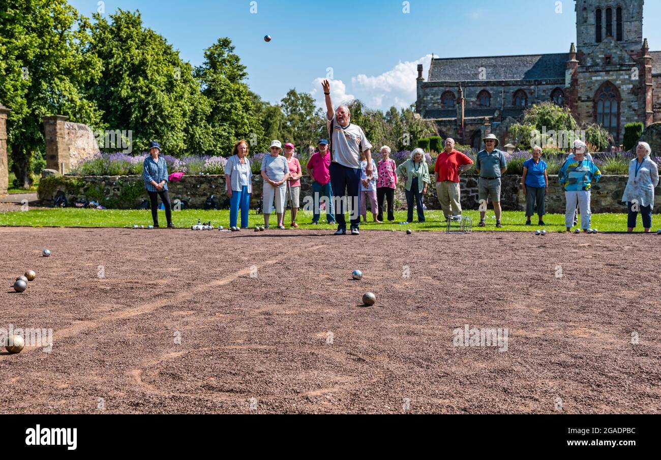 Ältere Menschen oder Rentner, die in Summer Sunshine, Haddington, East Lothian, Schottland, Großbritannien, eine Coaching-Lektion beim Spielen von Boule oder Petanque haben Stockfoto