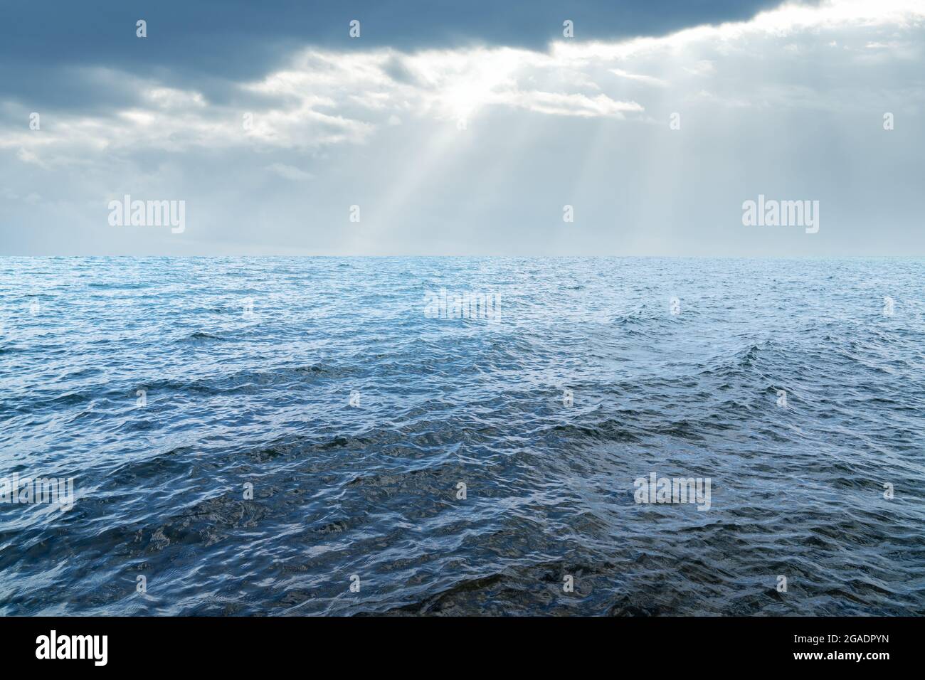 Nahaufnahme der Oberfläche des welligen blauen Meerwassers mit Sonne hinter den Wolken. Abstrakte Hintergrundtextur. Hochwertige Fotos Stockfoto