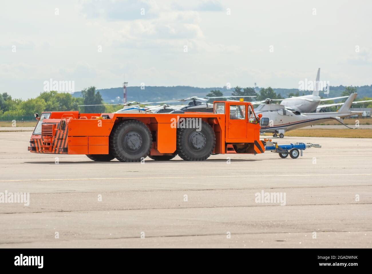 Der orangefarbene Schlepper des Flugplatzes fährt auf den Steuerwegen am Flughafen Stockfoto