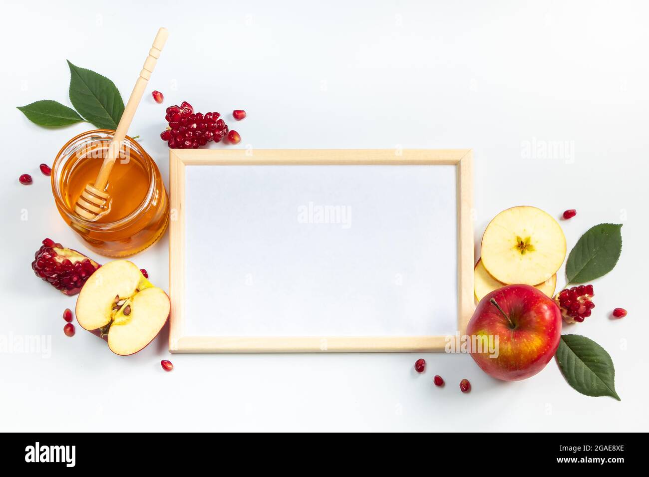 Happy Rosh Hashanah. Rahmen für Glückwunschtext. Äpfel, Granatäpfel und Honig auf weißem Hintergrund. Traditionelles Judentum Stockfoto