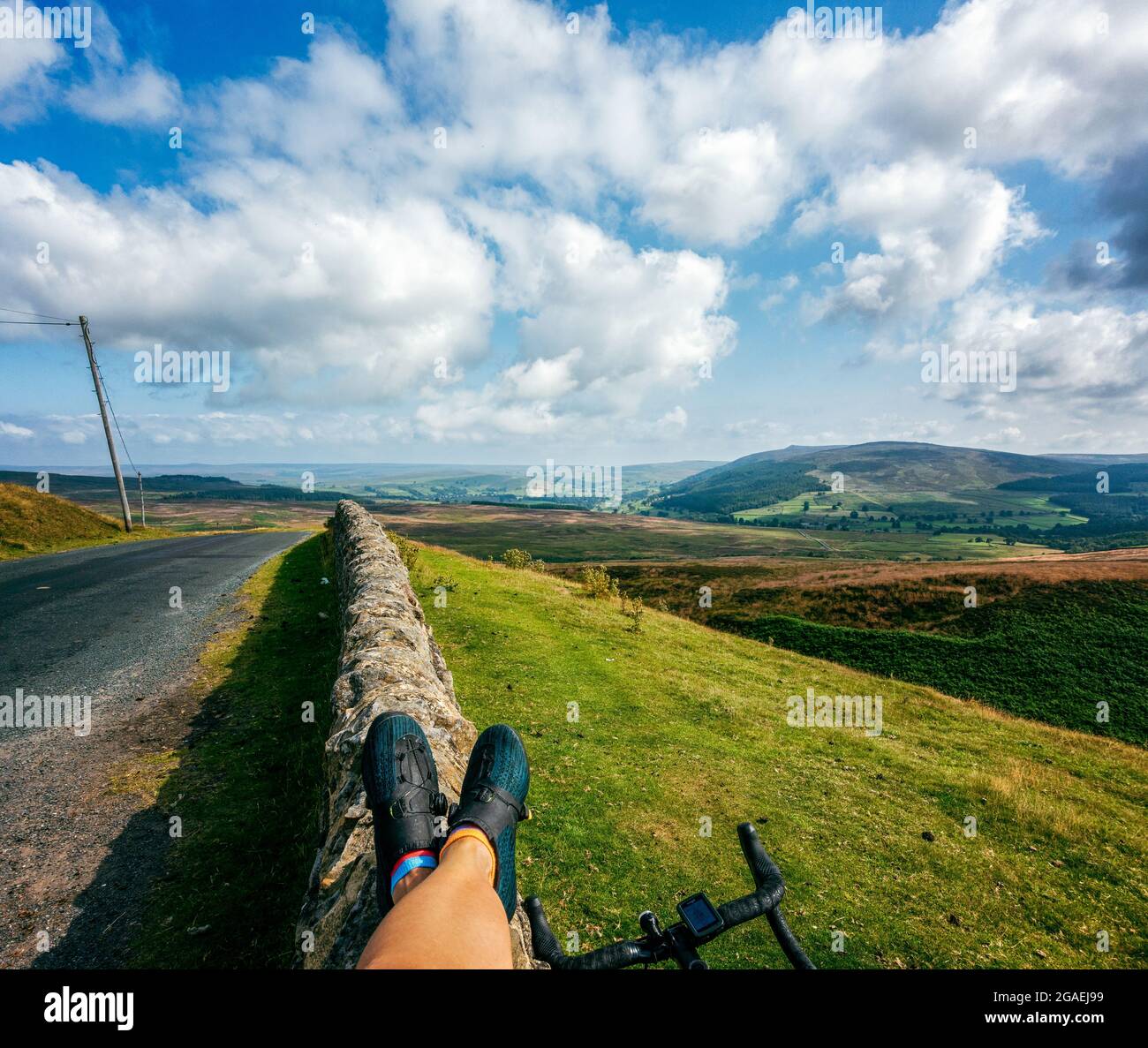 Radfahrerin in fizik-Schuhen, die eine Pause auf dem Gipfel des Cote de Barden Moor, Yorkshire Dales National Park, Großbritannien, macht Stockfoto