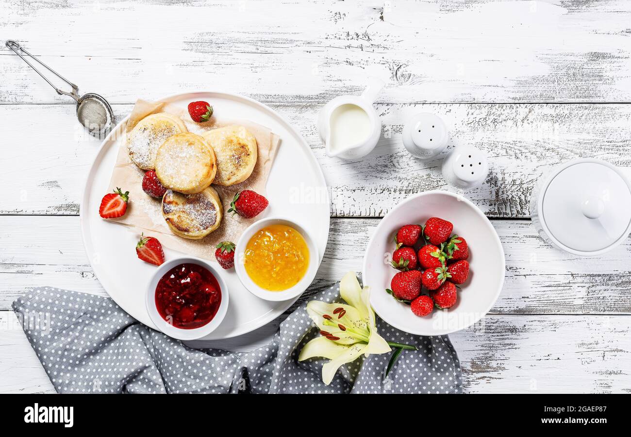 Pfannkuchen mit Quark und frischen Erdbeeren und Marmelade. Hüttenkäse-Pfannkuchen auf einem weißen Teller, bestreut mit Puderzucker. Köstliche hausgemachte Pause Stockfoto