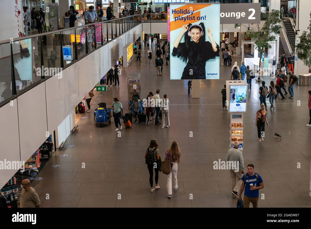 Amsterdam, Niederlande - 29. Juli 2021: Reisende wandern durch den Flughafen Shiphol. Vollständig geimpfte Reisende dürfen während einer Pandemie reisen, müssen aber auf Flughäfen und in Flugzeugen Masken tragen. Stockfoto