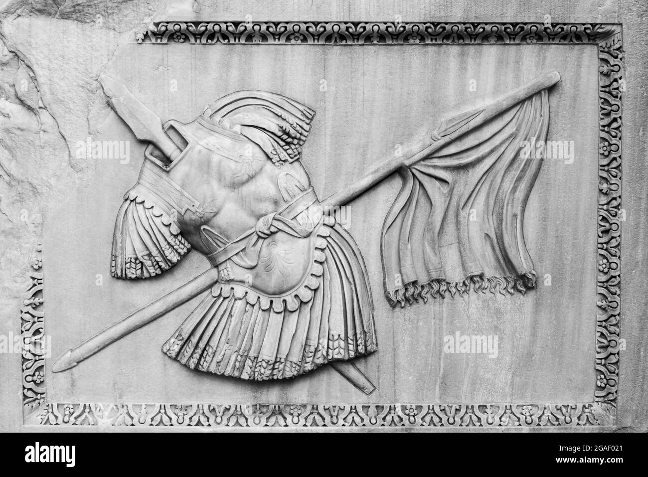 Schwarz-Weiß-Foto der alten römischen Rüstung und Flagge auf einer gerahmten Marmorwand eingraviert Stockfoto