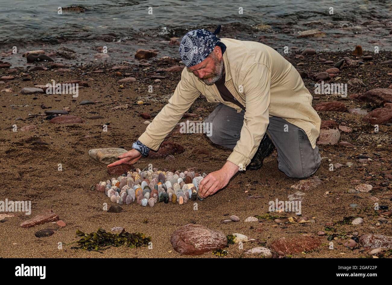 Der Landkünstler James Brunt kreiert am Strand, Dunbar, East Lothian, Schottland, Großbritannien, eine Stein- oder Felsskulptur Stockfoto