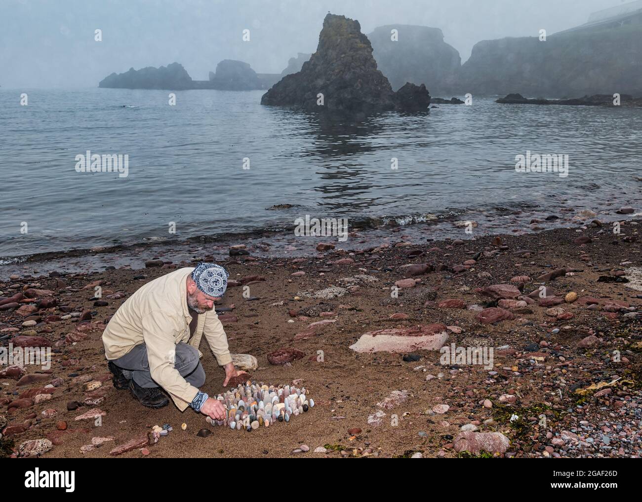 Der Landkünstler James Brunt kreiert am Strand, Dunbar, East Lothian, Schottland, Großbritannien, eine Stein- oder Felsskulptur Stockfoto