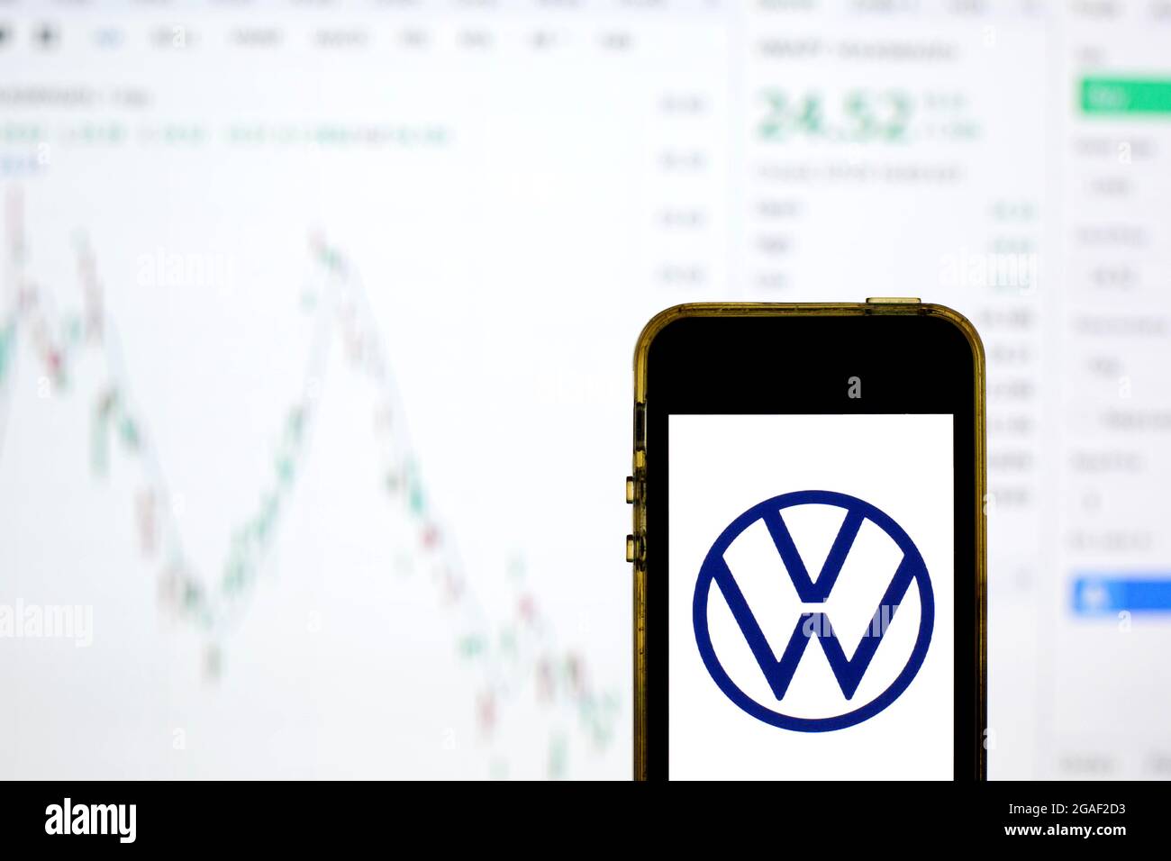 In dieser Abbildung ist ein Volkswagen-Logo auf einem Smartphone mit den Börseninformationen von Volkswagen im Hintergrund zu sehen. Stockfoto