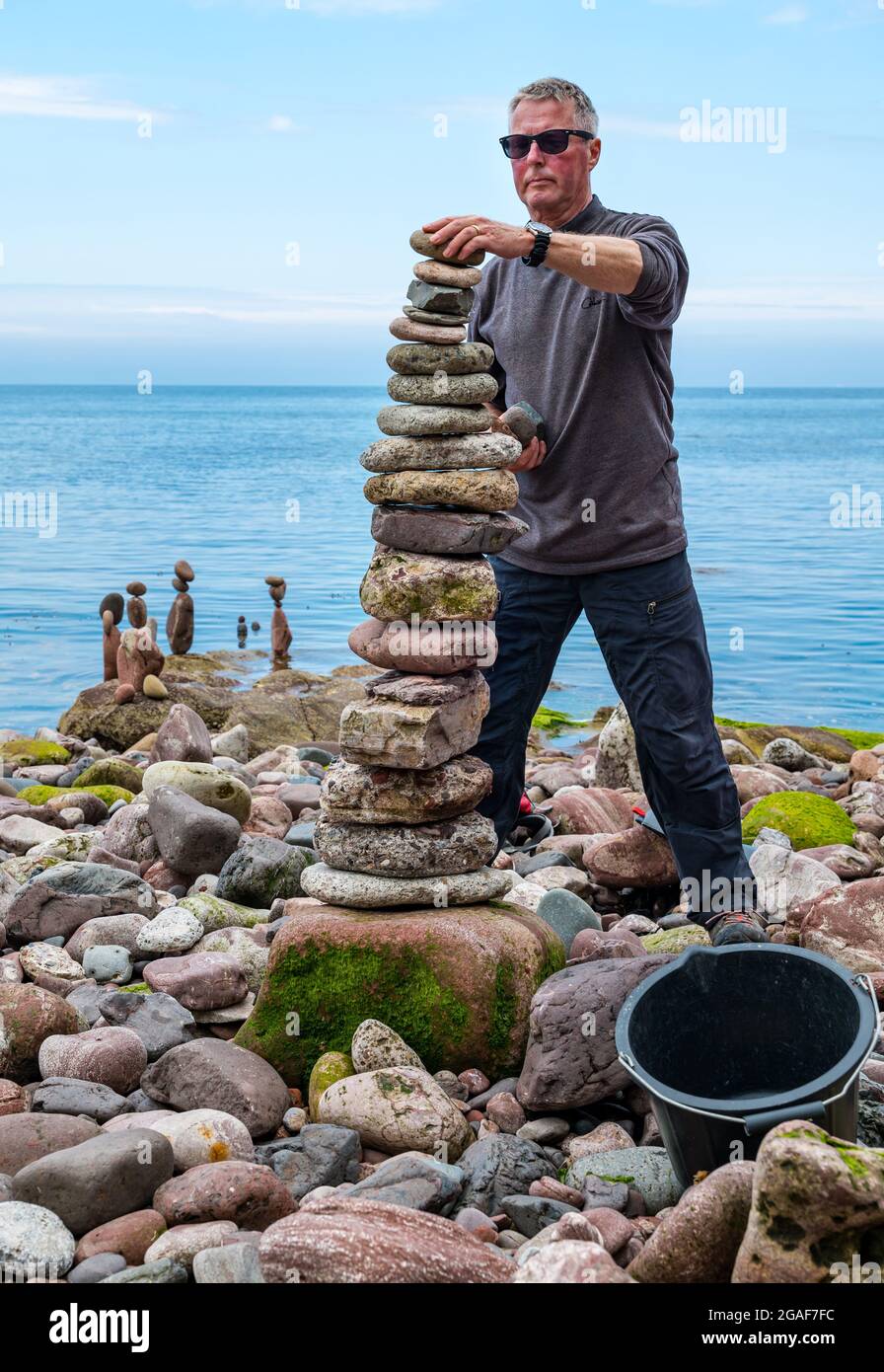Jonathon Kitching stapelt Steine in einem Turm bei der European Stone Stacking Championship am Strand, Dunbar, East Lothian, Schottland, Großbritannien Stockfoto
