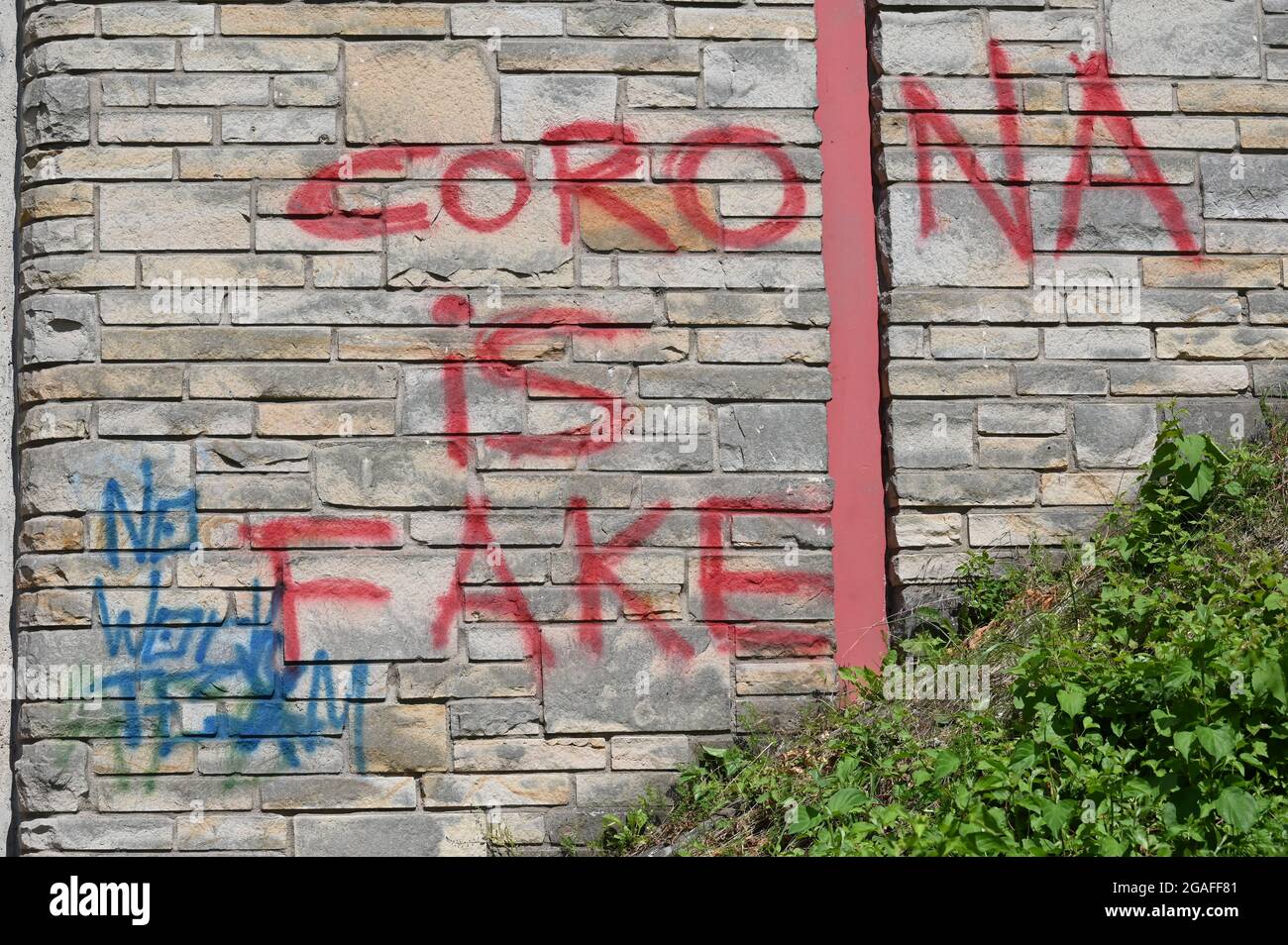 Sandsteinwand mit Schriftzug: Corona ist gefälscht Stockfoto