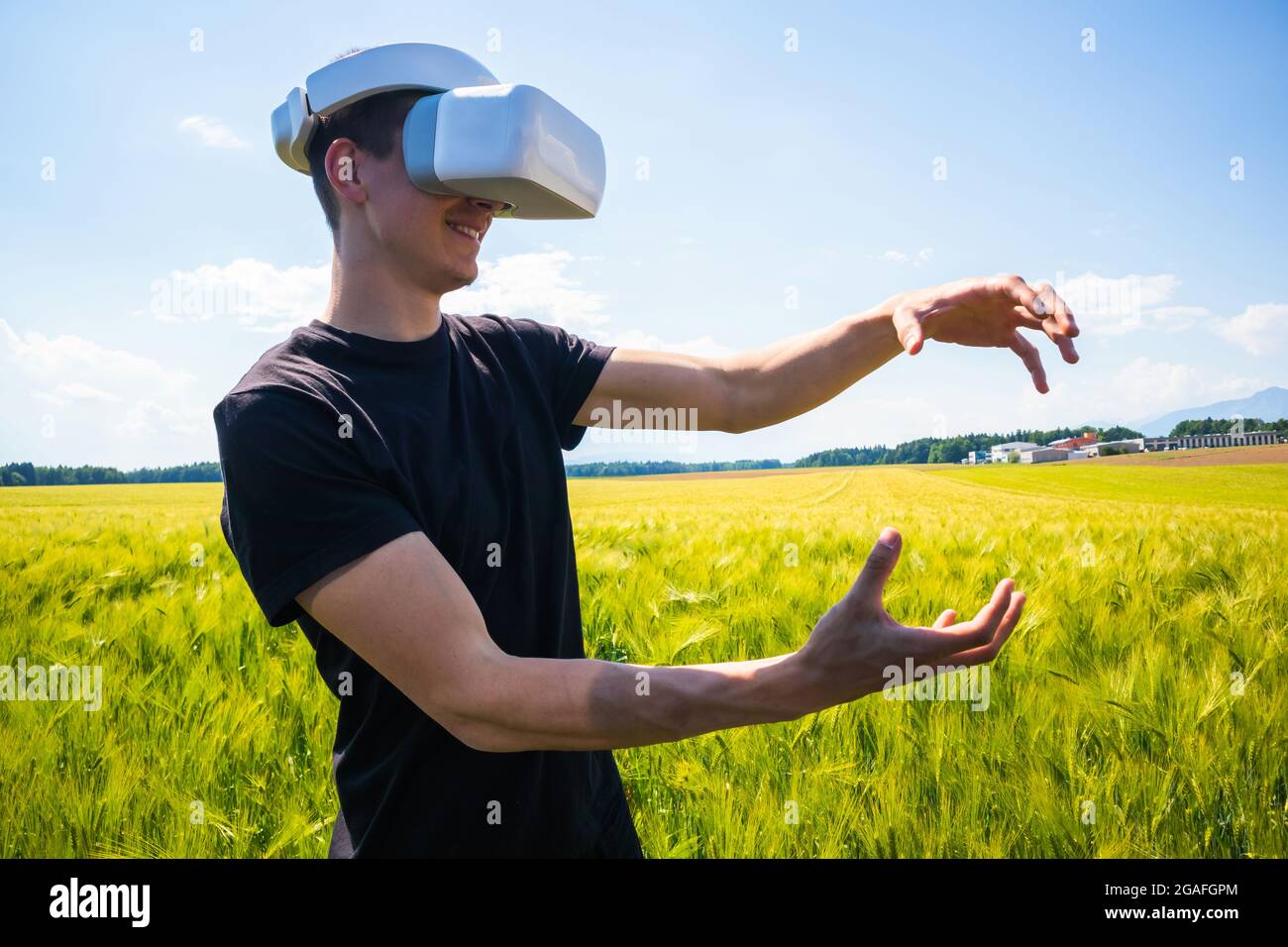 Mann mit Virtual-Reality-Brille draußen in der Natur auf einem Weizenanbaugebiet. Stockfoto