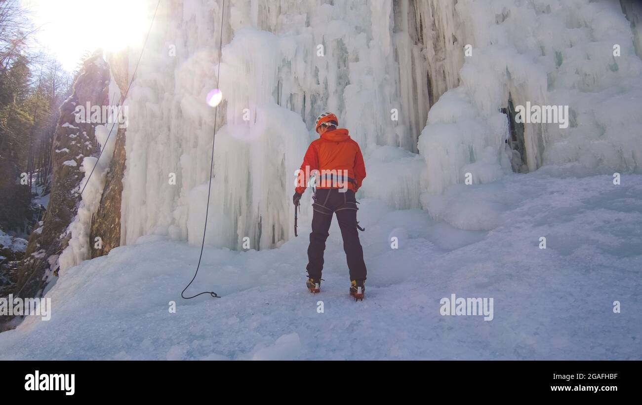Nahaufnahme eines männlichen kaukasischen Eiskletterers, der ein Seil an sein Geschirr bindet und sich auf einen Aufstieg vorbereitet Stockfoto