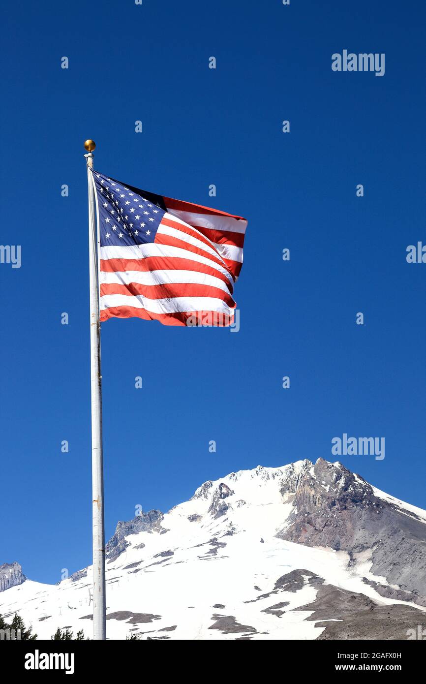 Die amerikanische Flagge, die mit Mt Hood (Oregon) im Hintergrund fliegt. Stockfoto