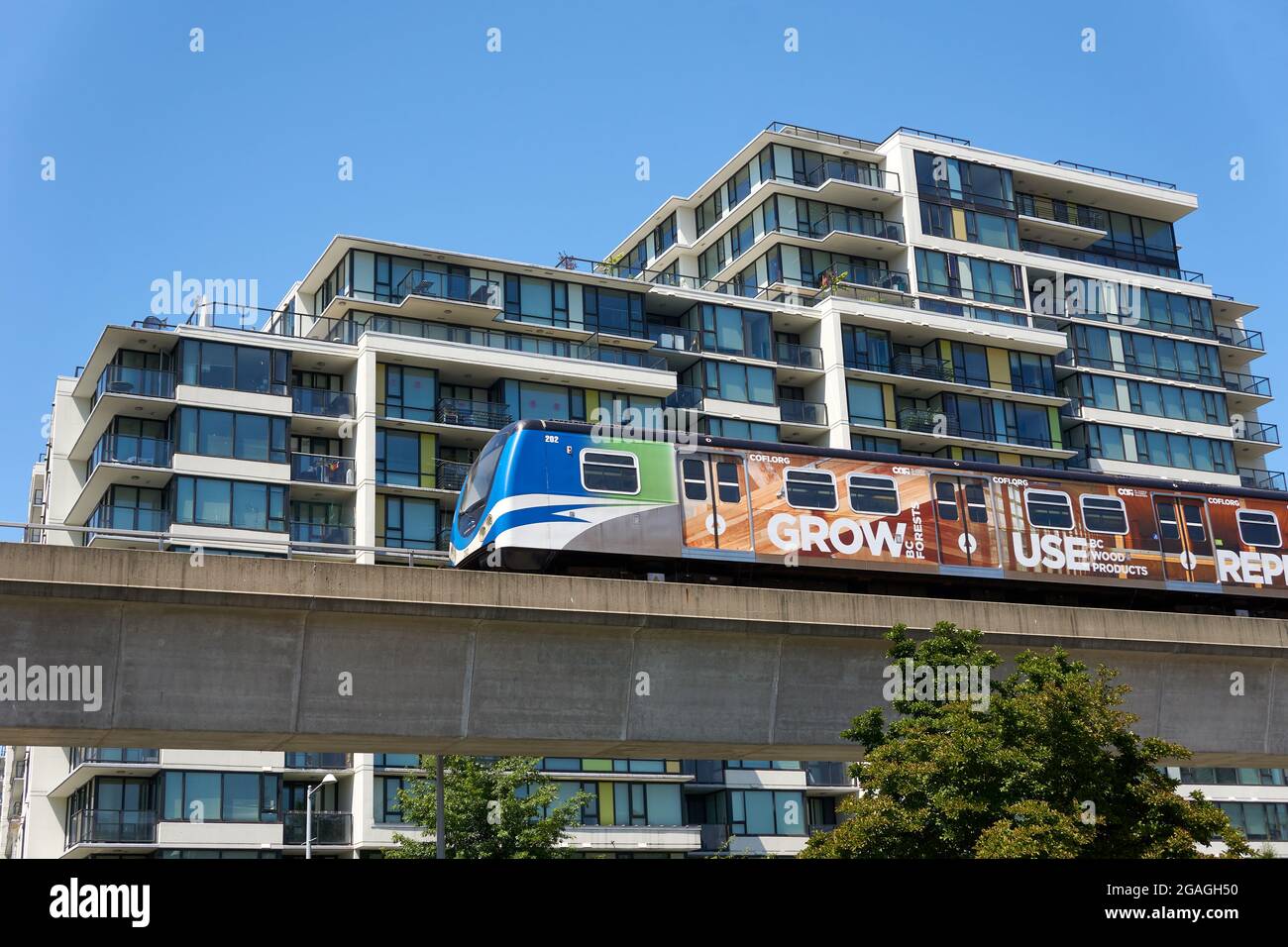 Skytrain Hochbahn-Schnellbahn, die an einem modernen Wohngebäude in Richmond, British Columbia, Kanada, vorbeifährt Stockfoto