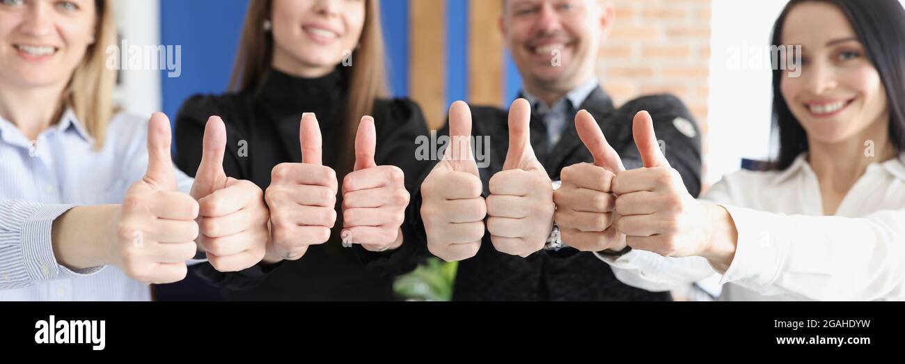Lächelnde Geschäftsleute zeigen Daumen nach oben, stehen im Büro Stockfoto