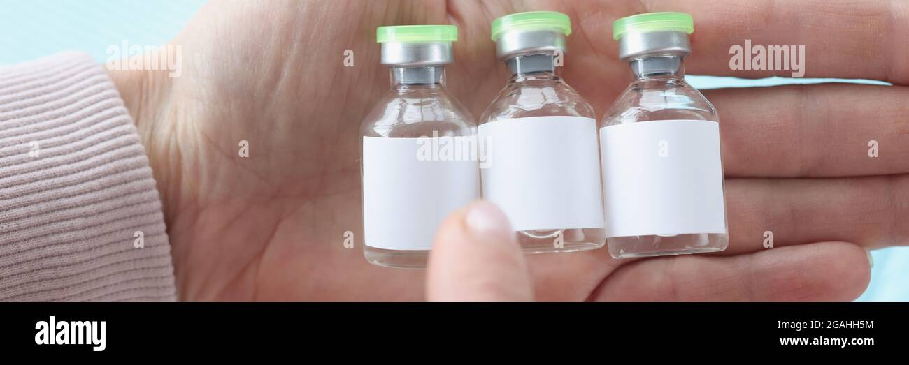Drei Fläschchen Coronavirus-Impfstoff der Wahl in der Hand halten Stockfoto