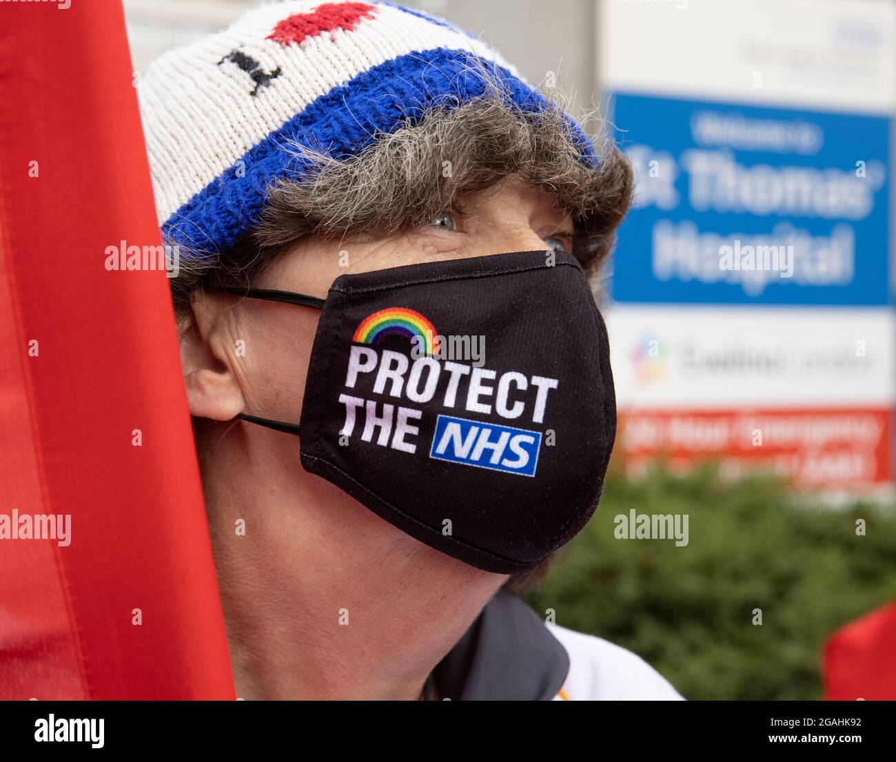 Eine Frau trägt eine Gesichtsmaske mit „Protect the NHS“ vor dem St. Thomas's Hospital. Die Mitarbeiter des NHS sind gegen das Angebot der Regierung zu 3 %. Stockfoto