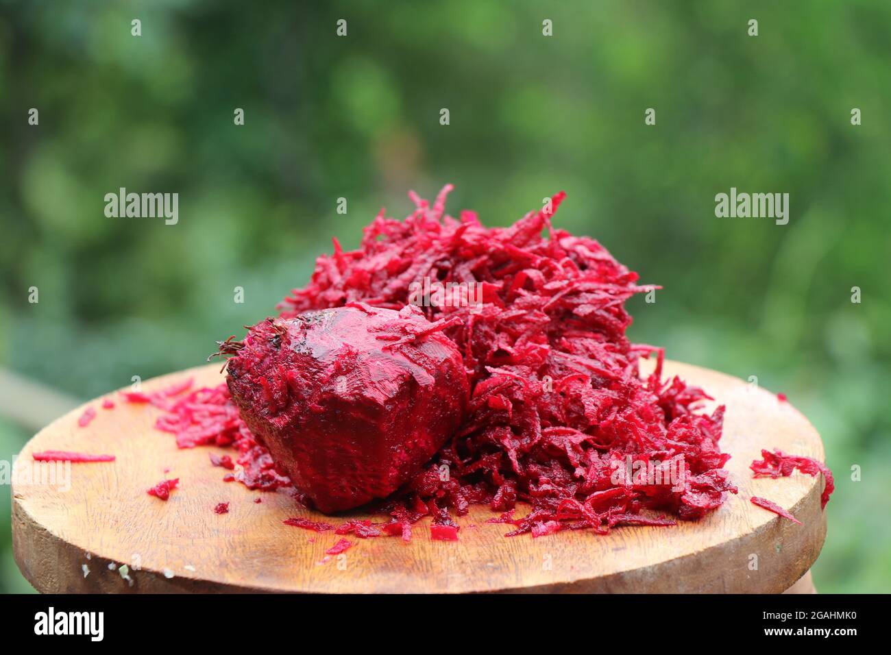 Haufen geriebener roter Rote Beete in Holzschneidebrett auf Naturhintergrund Stockfoto