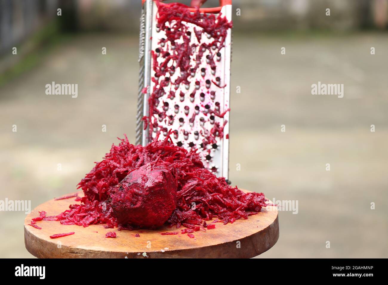 Frisch geriebene Rote Bete mit Gemüseriebe aus Edelstahl in der Hand gehalten Stockfoto