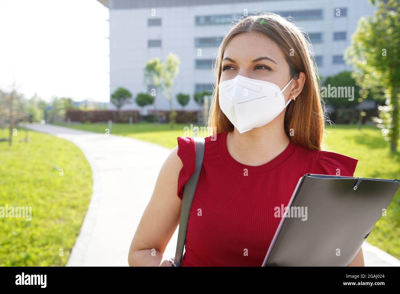 Universitätsstudentin Mädchen mit FFP2 KN95 Gesichtsmaske hält Ordner auf der Seite im Freien suchen Stockfoto