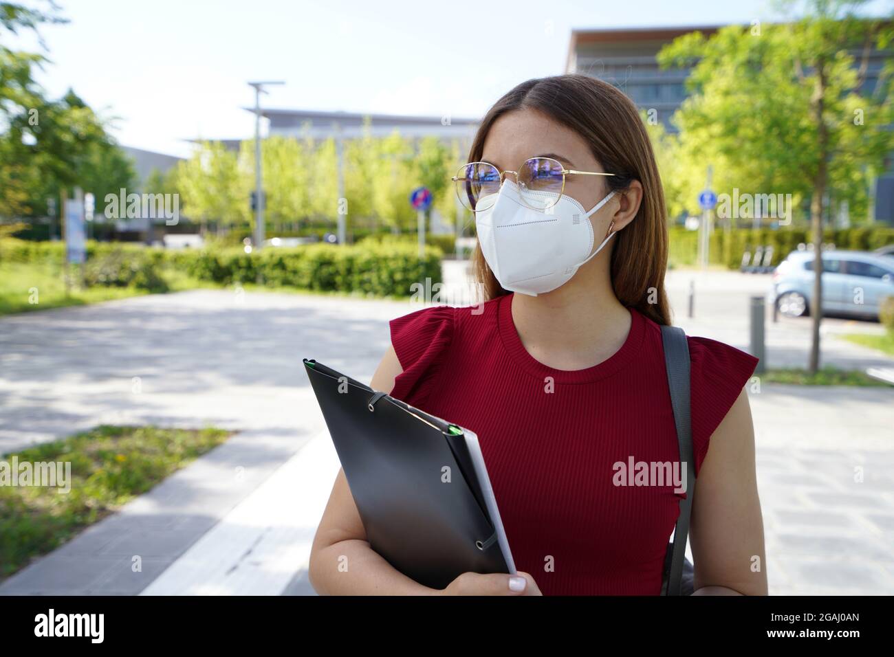Schöne Student Mädchen trägt FFP2 Schutzmaske zu Fuß in der modernen Straße Stockfoto