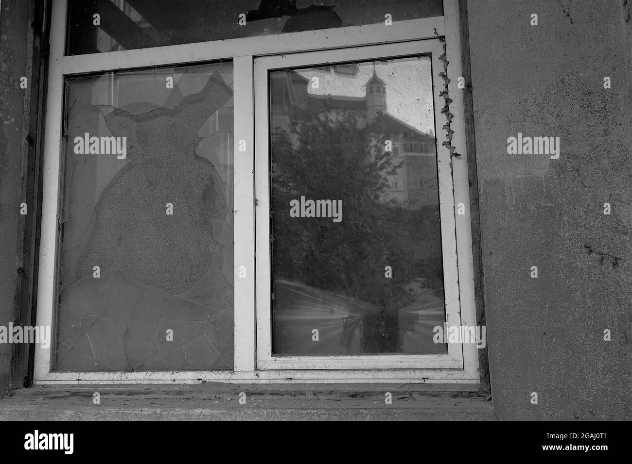 Altes kaputtes Fenster in schwarz-weißer Farbe. Eine Fensterscheibe wird durch Karton ersetzt. Stockfoto