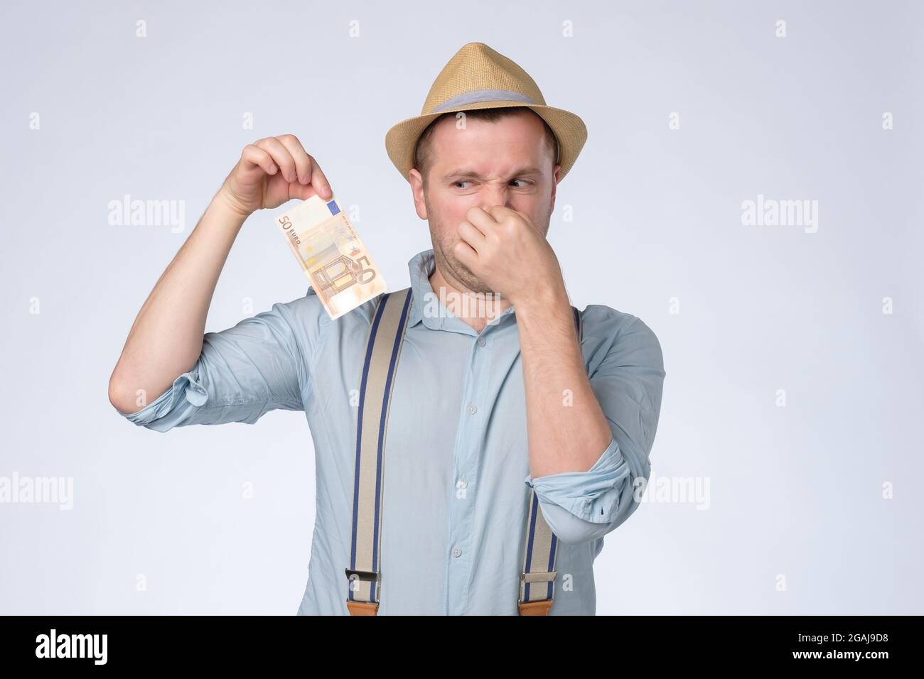 Junger Mann riecht etwas stinkend und ekelhaft vom Geld. Stockfoto