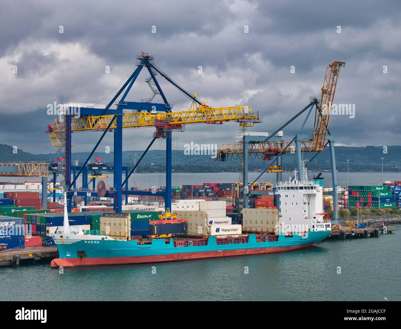 Das Containerschiff Ragna lädt und lädt an einem bewölkten Sonntagmorgen im Juli 2021 am Containerterminal im Hafen von Belfast ein Stockfoto