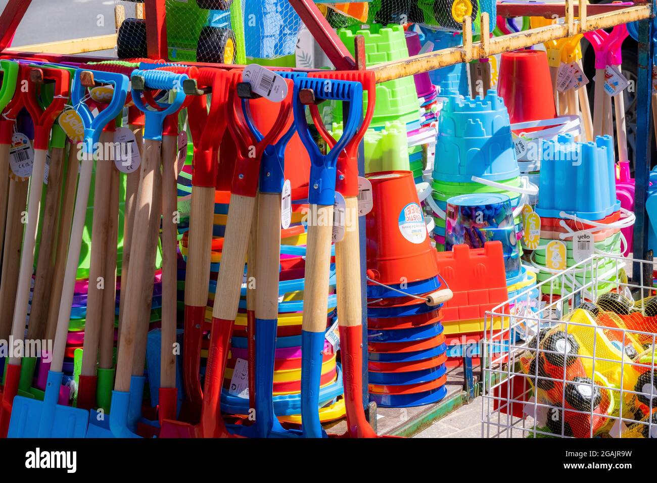 Bunte Kinder-Plastikeimer und -Spaten; Strandspielzeug zum Verkauf am Meer in Großbritannien. Stockfoto
