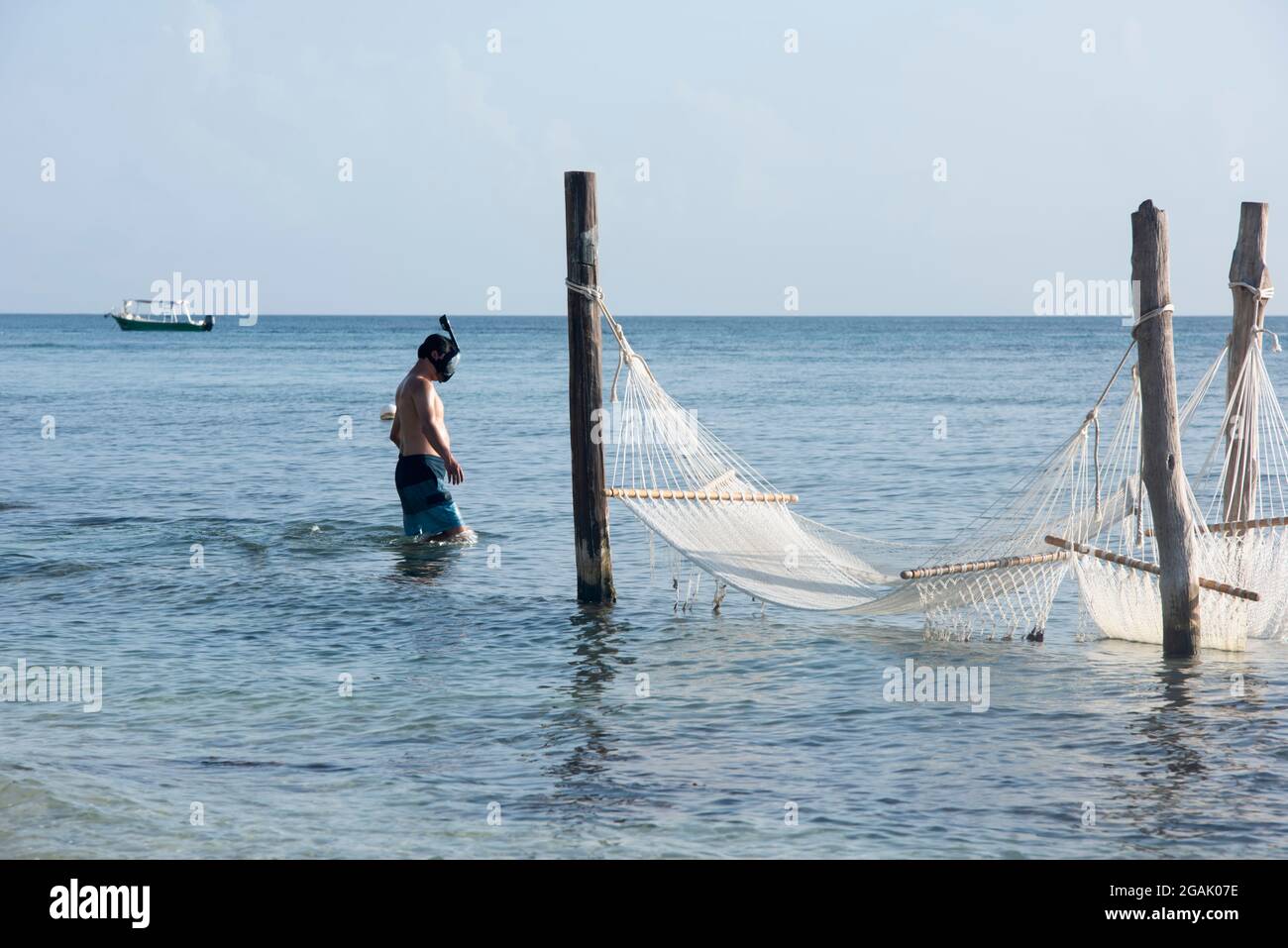 Mann mit Schnorchelmaske in der Nähe von Hängematten am Karibischen Meer, der Insel Cozumel, Mexiko. Im Hintergrund ist der blaue Himmel zu sehen. Stockfoto