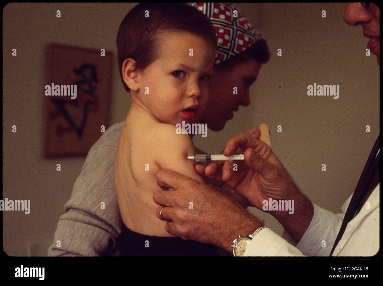 Das Kind, das in den Armen seiner Mutter gehalten wird, erhält eine Impfung von einem Arzt, ohne Ort, 1970. (Foto von Bernard Gotfryd/LOC/RBM Vintage Images) Stockfoto