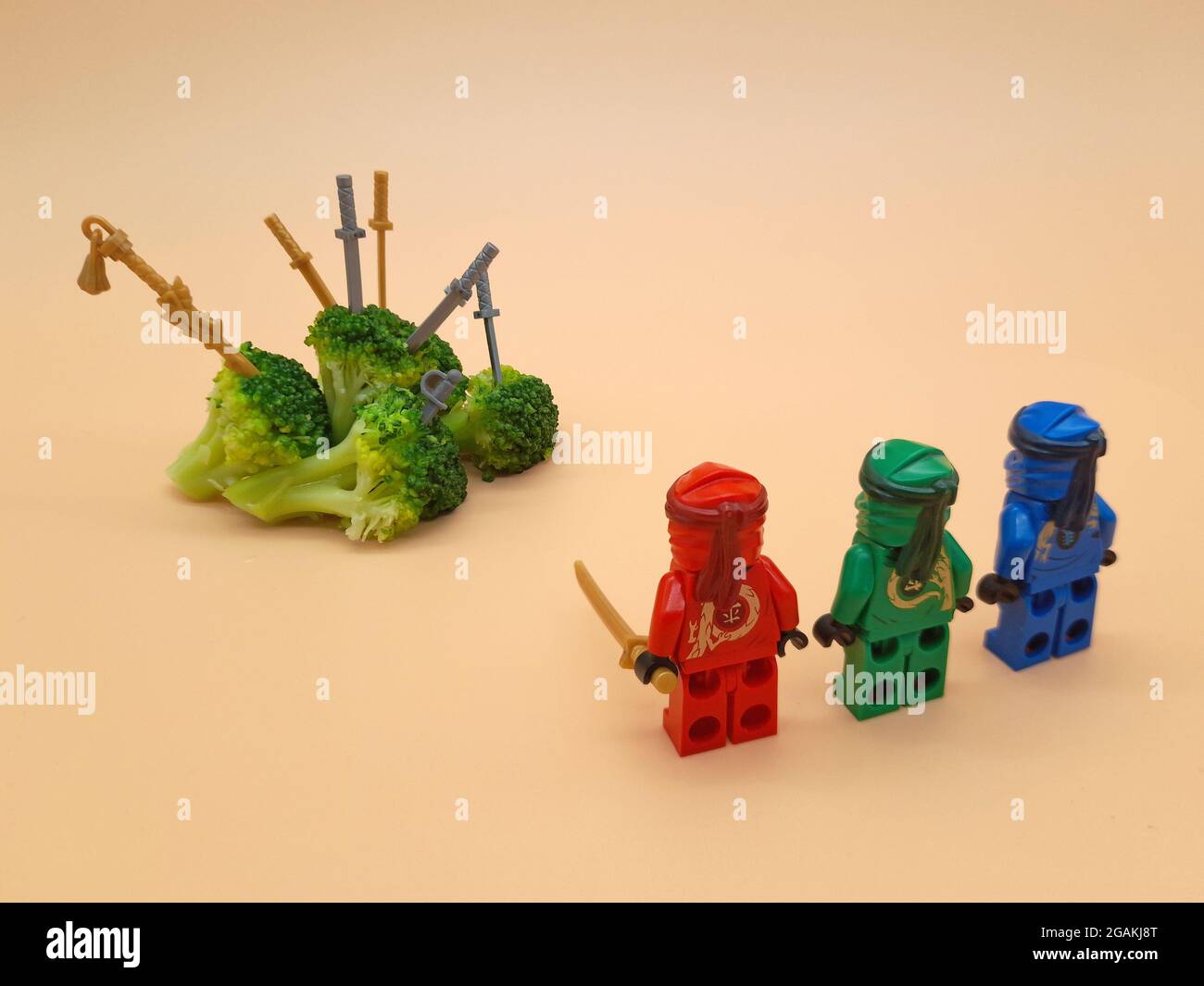 Drei LEGO Ninjas haben Brokkoli angegriffen und viele Schwerter hineingeworfen. Ein Protest eines Kindes, das kein Gemüse essen will Stockfoto