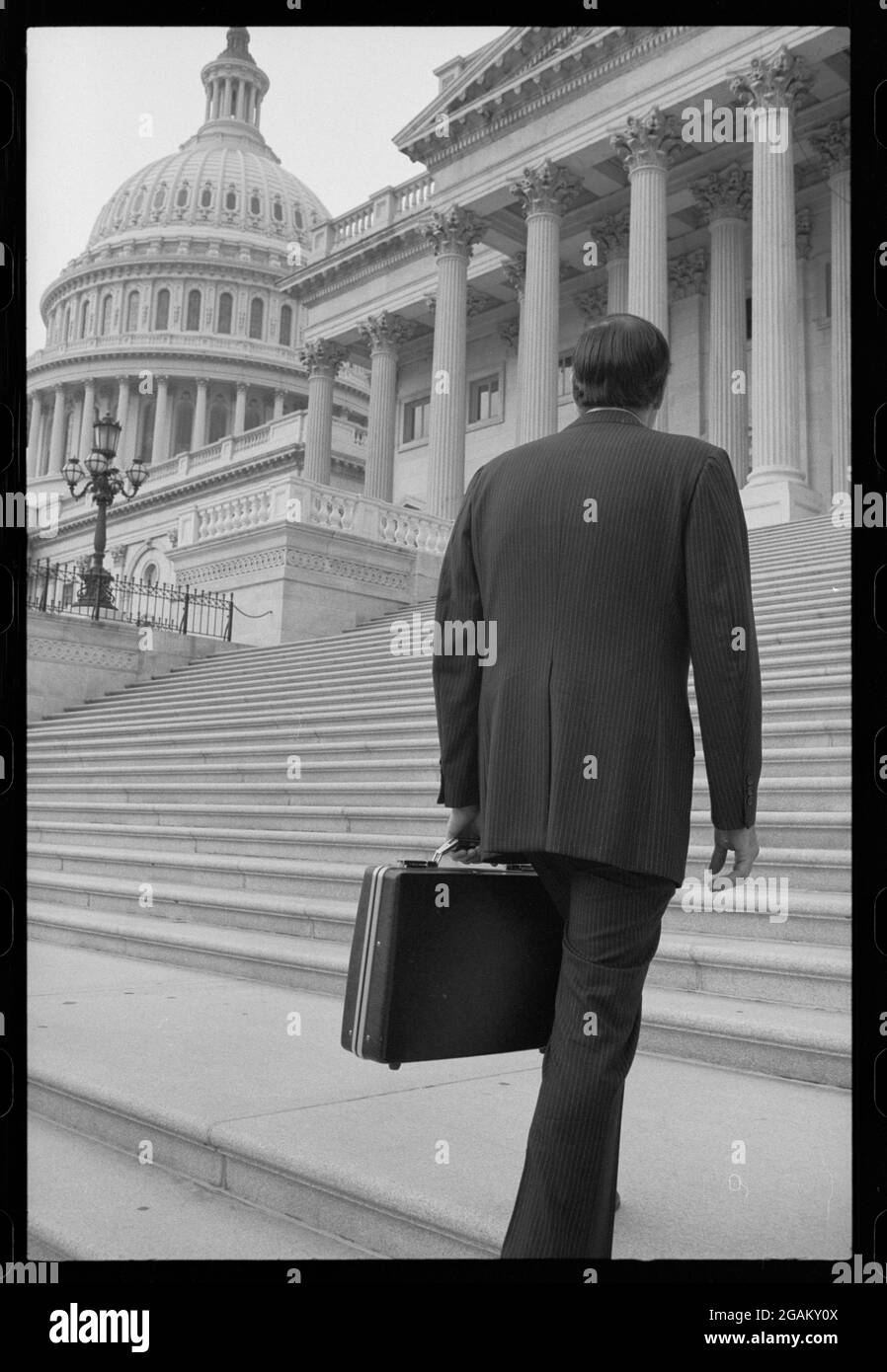Rückansicht eines Mannes, der einen Business-Anzug trägt und eine Aktentasche trägt, die die Stufen zum Kapitolgebäude der Vereinigten Staaten führt, mit dem Capitol Dome links, Washington, DC, 7/9/1977. (Foto von Warren K Leffler/US News & World Report Collection/RBM Vintage Images) Stockfoto