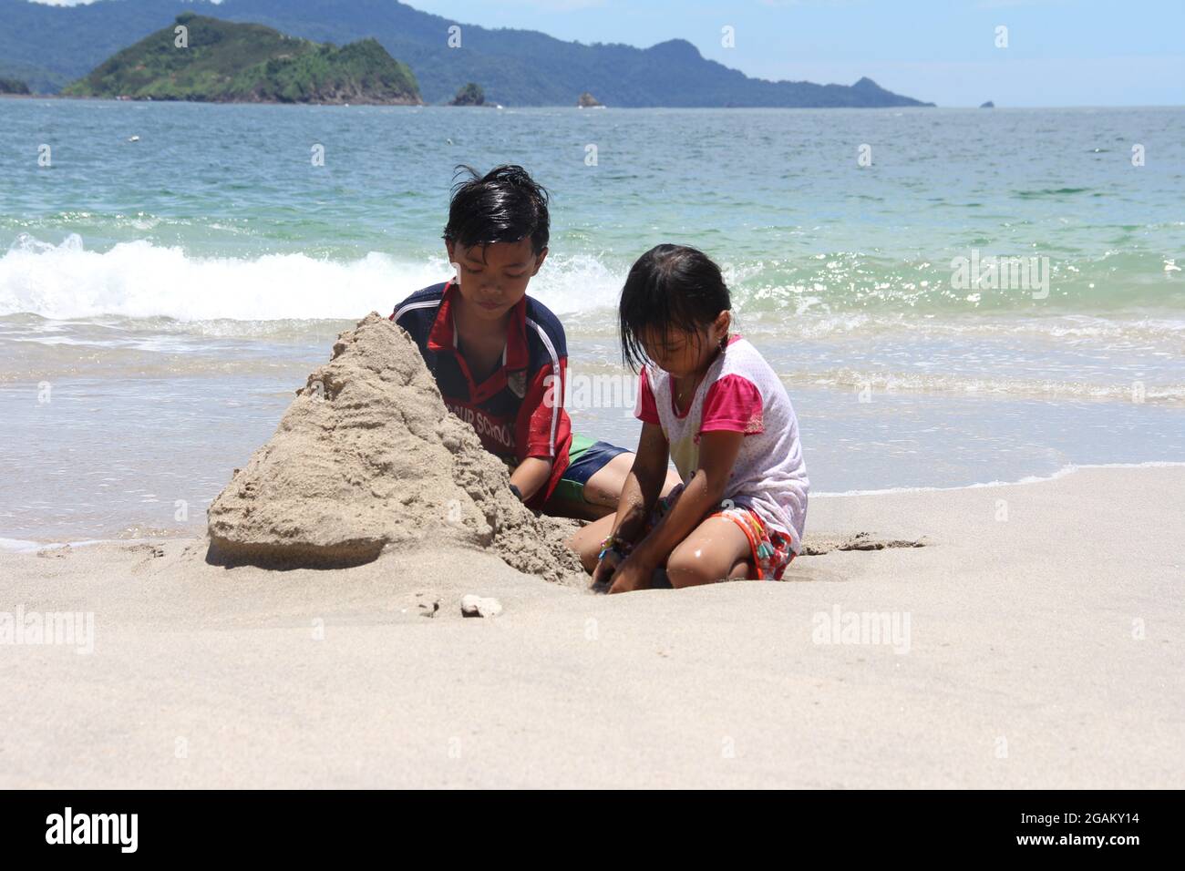 Jember, Indonesien - 14. Februar 2016. Brüder und Schwestern bauen Sandburgen am Strand von Papuma. Stockfoto