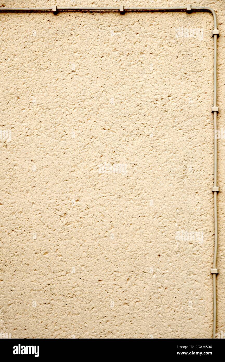 Raue verputzte Wand, mit Elektrokabel umrahmt; grunziger Hintergrund mit Kopierraum Stockfoto