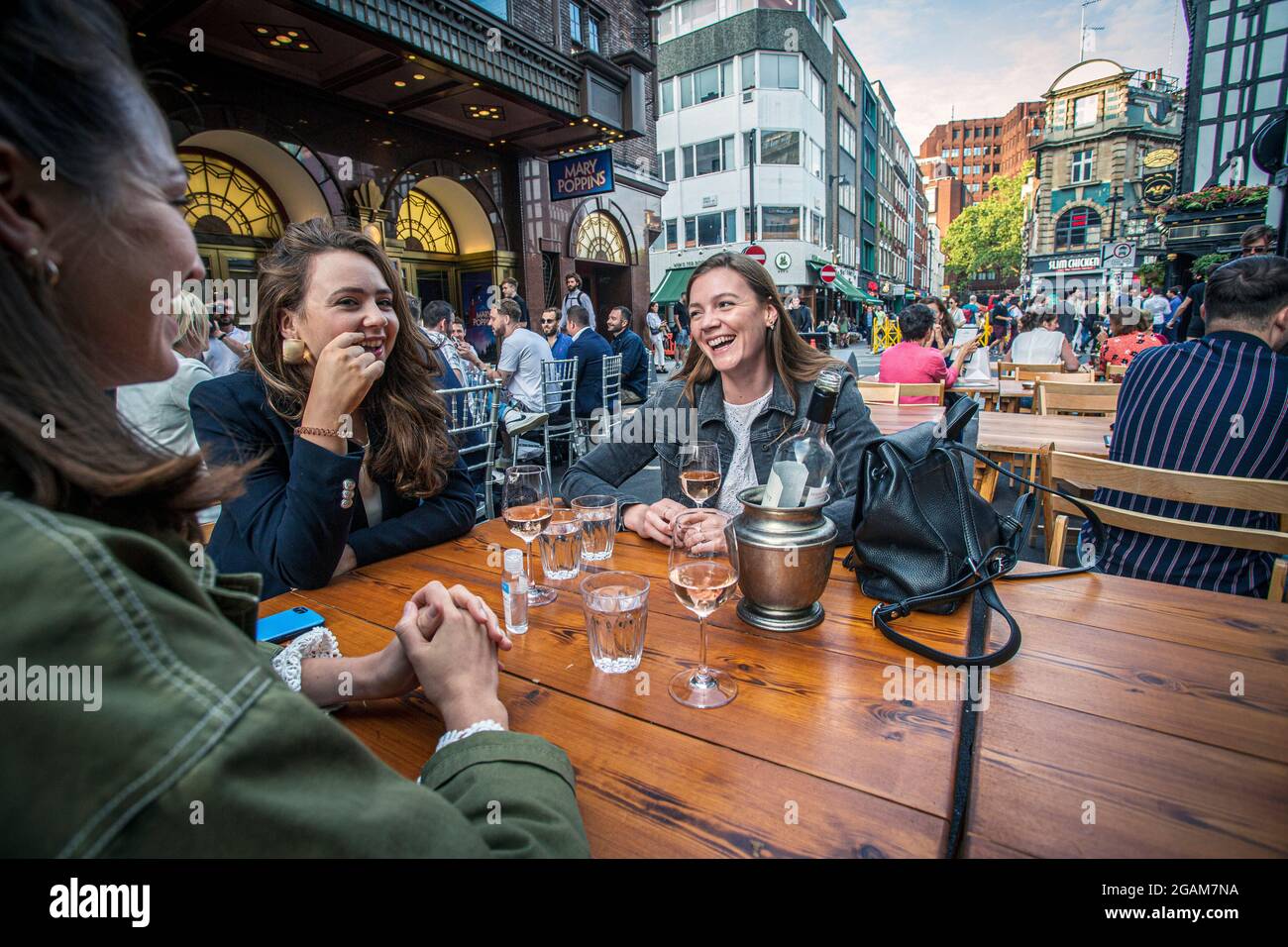 Junge Frauen feiern den „Tag der Freiheit“, der über ein Jahr der COVID-19-Sperrbeschränkungen endet in England, wo Menschen auf Tischen trinken, die draußen auf Ol platziert sind Stockfoto