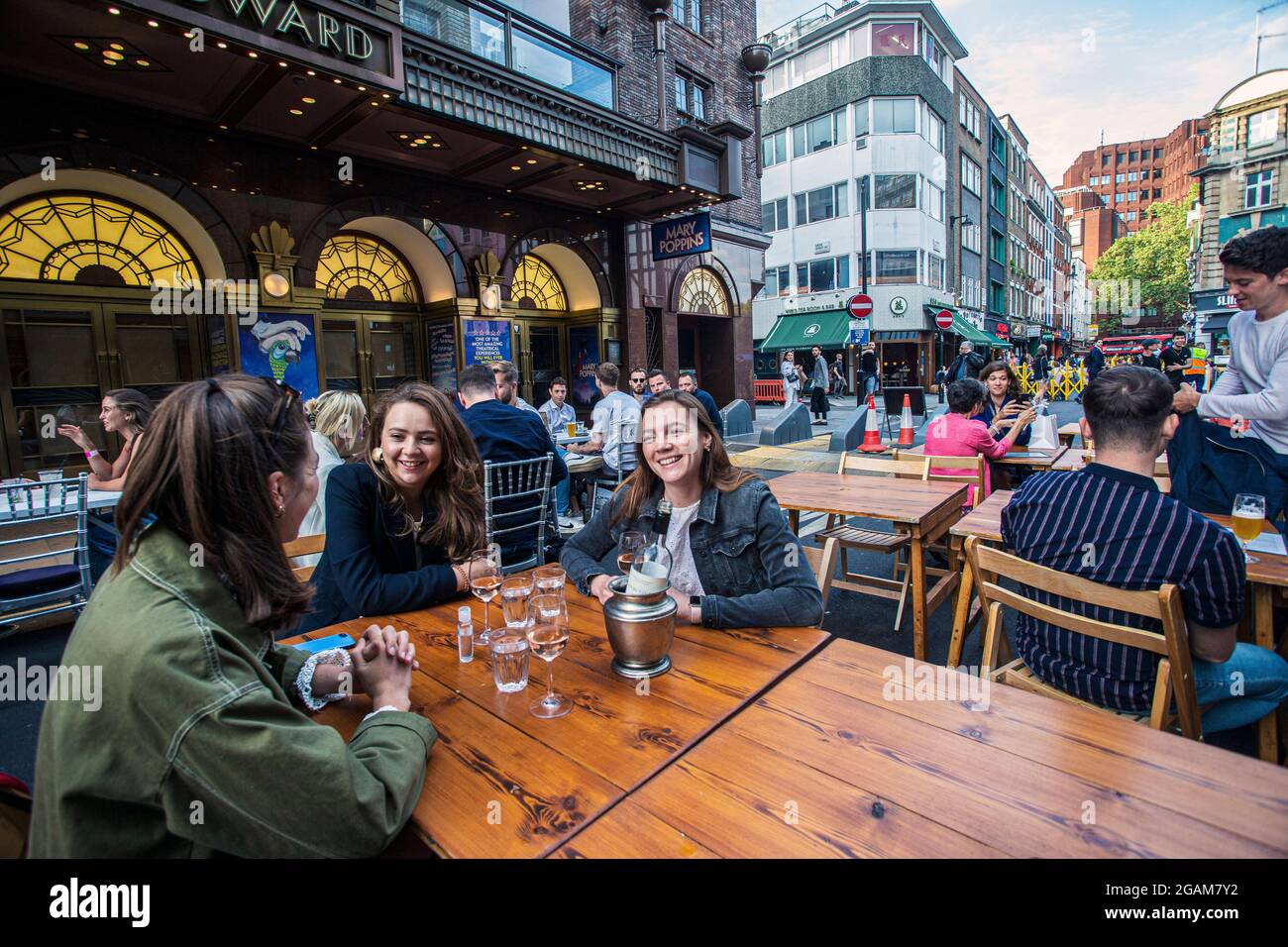 Junge Frauen feiern den „Tag der Freiheit“, der über ein Jahr der COVID-19-Sperrbeschränkungen endet in England, wo Menschen auf Tischen trinken, die draußen auf Ol platziert sind Stockfoto