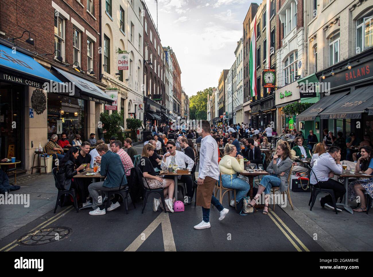 Menschen, die auf Restauranttischen essen, die draußen in der Frith Street in Soho, London, Großbritannien, aufgestellt sind Stockfoto