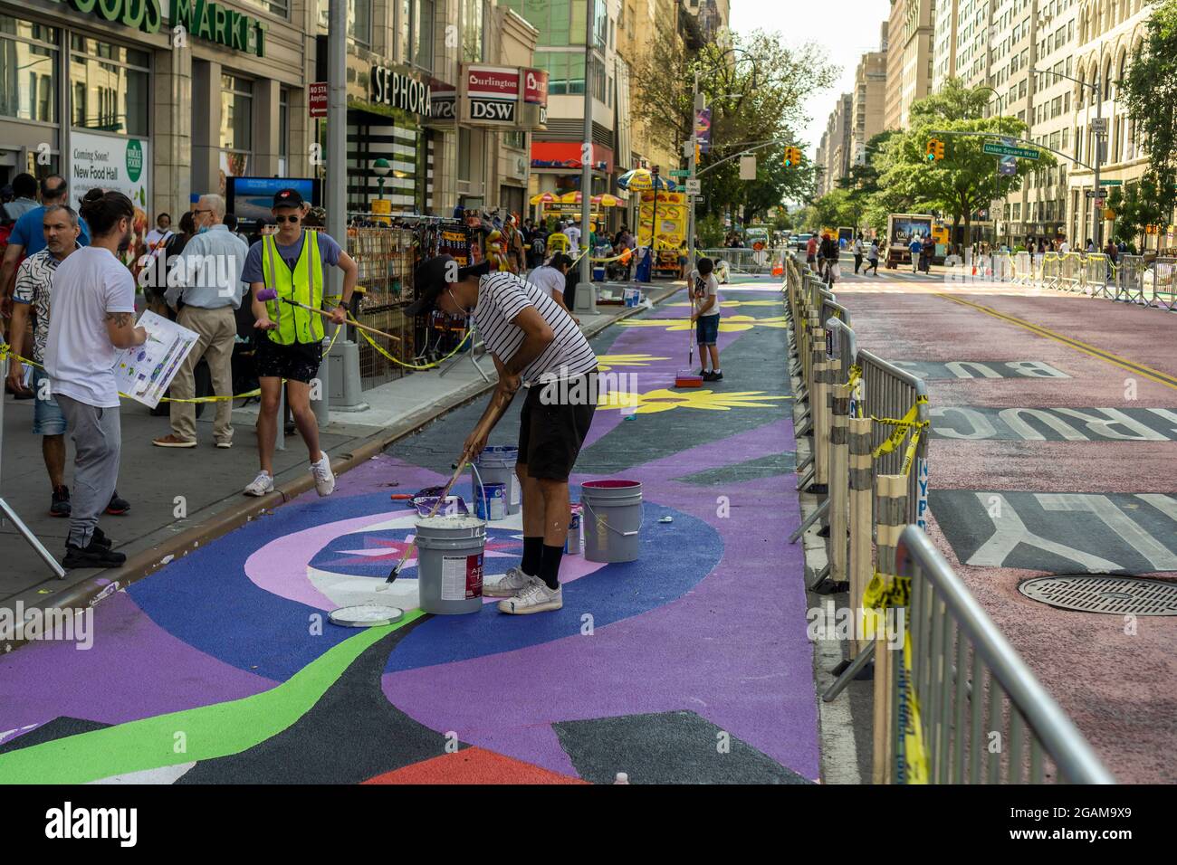 Gemeinsam mit den Künstlern GERALUZ und Werc beenden Freiwillige am Freitag, dem 30. Juli 2021, ihr zweiteiliges riesiges Wandgemälde mit dem Titel Collective Visions, das die 14th Street auf dem Union Square in New York schmückt. Die Wandmalereien besetzen Fußgängerzonen, die durch die Implementierung des 14. St Busway geschaffen wurden und von der NYC Dept. Of Transportation und der Union Square Partnership BID gehostet werden. (© Richard B. Levine) Stockfoto
