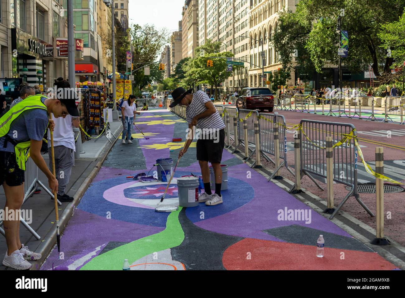 Gemeinsam mit den Künstlern GERALUZ und Werc beenden Freiwillige am Freitag, dem 30. Juli 2021, ihr zweiteiliges riesiges Wandgemälde mit dem Titel Collective Visions, das die 14th Street auf dem Union Square in New York schmückt. Die Wandmalereien besetzen Fußgängerzonen, die durch die Implementierung des 14. St Busway geschaffen wurden und von der NYC Dept. Of Transportation und der Union Square Partnership BID gehostet werden. (© Richard B. Levine) Stockfoto
