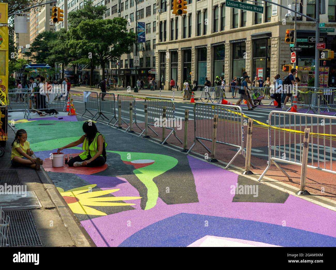 Gemeinsam mit den Künstlern GERALUZ und Werc beenden Freiwillige am Freitag, dem 30. Juli 2021, ihr zweiteiliges riesiges Wandgemälde mit dem Titel Collective Visions, das die 14th Street auf dem Union Square in New York schmückt. Die Wandmalereien besetzen Fußgängerzonen, die durch die Implementierung des 14. St Busway geschaffen wurden und von der NYC Dept. Of Transportation und der Union Square Partnership BID gehostet werden. (© Richard B. Levine) Stockfoto