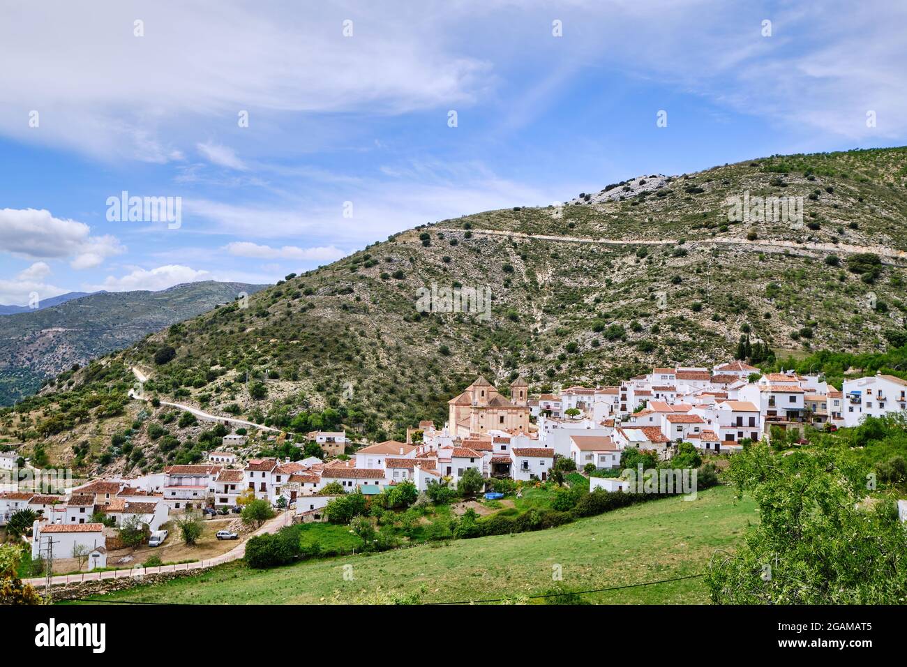 Blick auf weißes Dorf mit Bergen im Hintergrund, Alpandeire, Serrania de Ronda, Provinz Malaga, Andalusien, Spanien. Stockfoto