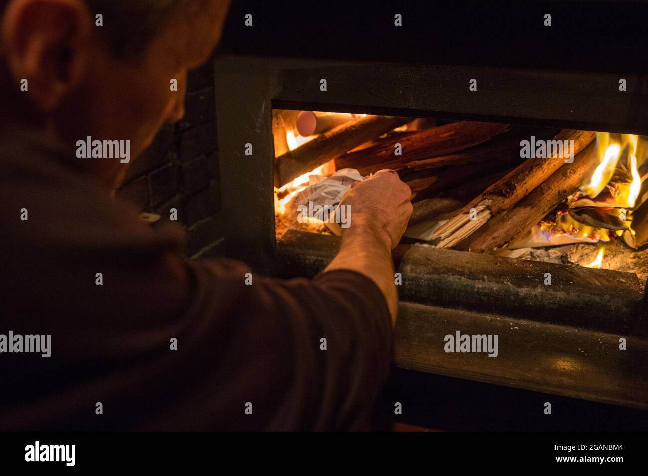Ein Mann legt Holz in einen Kamin, drinnen, Mendocino, Kalifornien, USA. Stockfoto