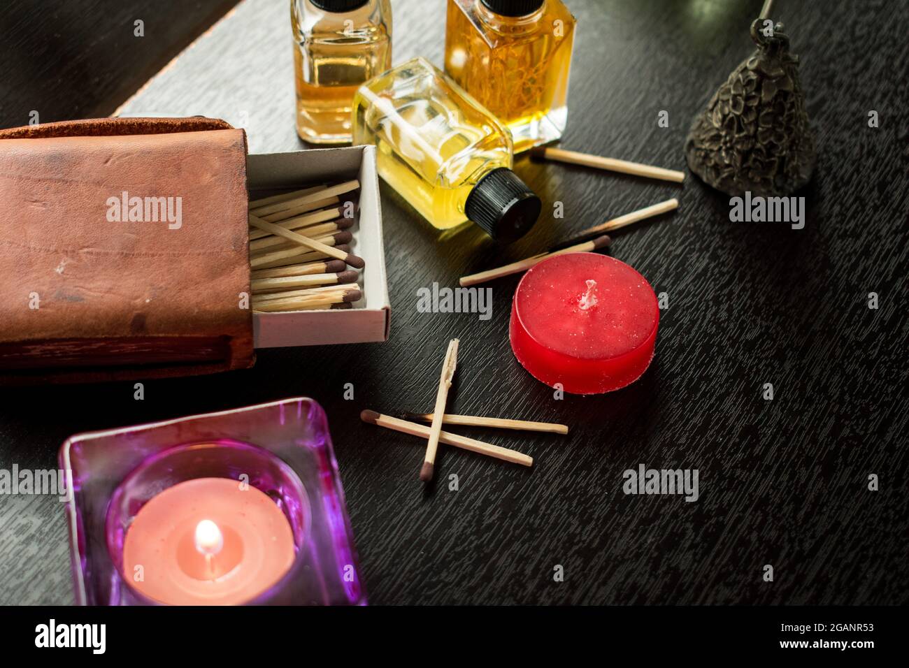 Hoch anwinklige Aufnahme einer dekorativen Kerze und ätherischem Öl in kleinen Gläsern mit Streichhölzern auf dem Tisch Stockfoto