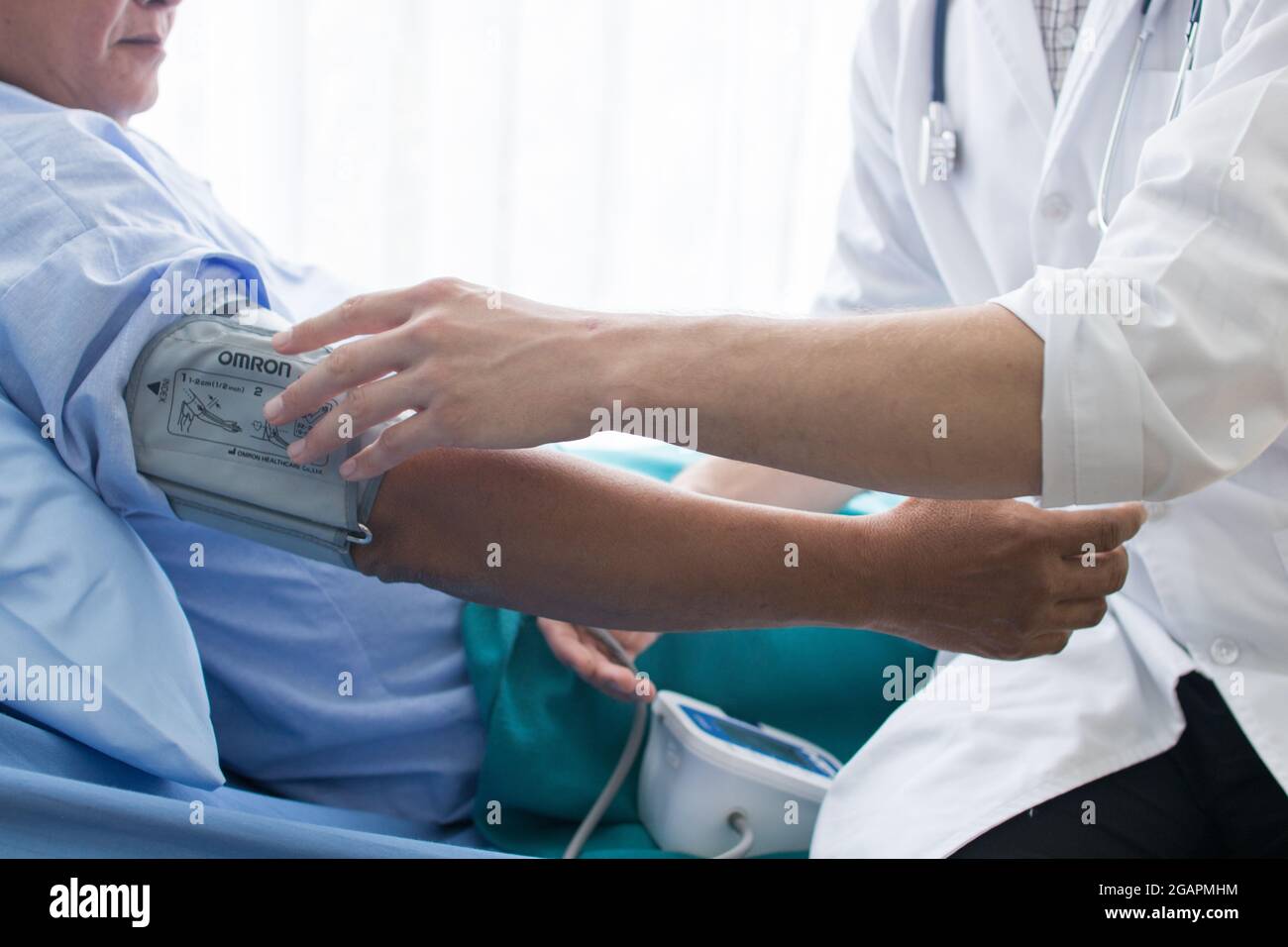 Nahaufnahme des Arztes, der im Krankenhaus arbeitet und das Blutdruckmessgerät an der Hand eines älteren Mannes anpasst Stockfoto