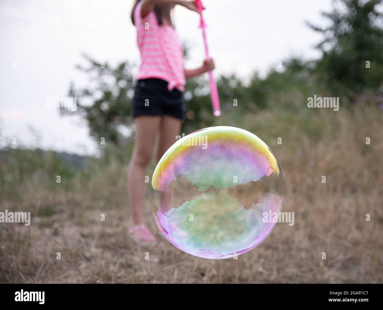 Ein kleines Mädchen in der Natur spielt mit großen Seifenblasen. Stockfoto